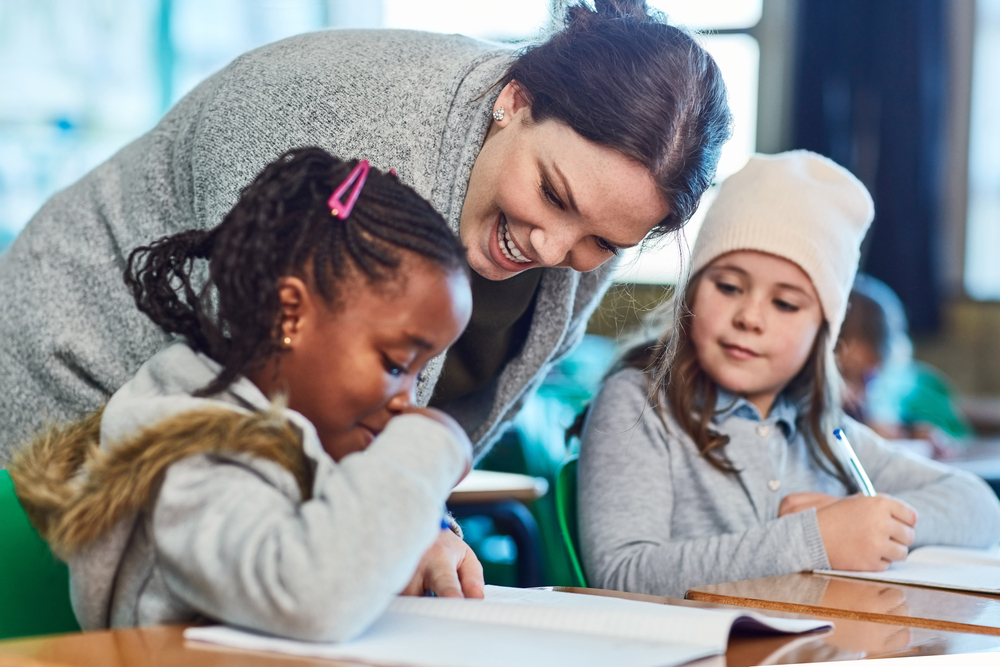Dedicated in helping her students understand the work. elementary school girls getting help from their teacher in the classroom.